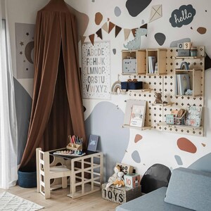 Cube desk and chair set arranged in a Scandinavian nursery with a pegboard wall.