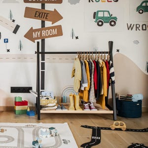 Black wooden garment rack filled with outerwear, helping dads keep playroom floors clear of seasonal coats and jackets.