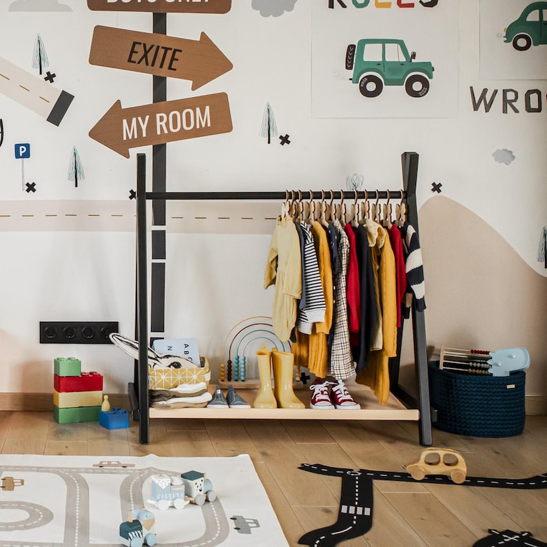 Black wooden garment rack filled with outerwear, helping dads keep playroom floors clear of seasonal coats and jackets.