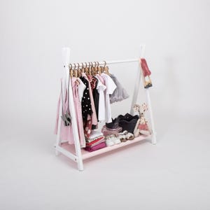 White wooden clothing rack with a soft pink fabric storage shelf, serving as a lovely baby shower gift for expectant mothers.