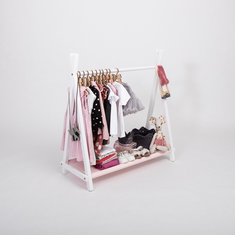 White wooden clothing rack with a soft pink fabric storage shelf, serving as a lovely baby shower gift for expectant mothers.