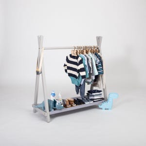 Grey wooden wardrobe stand displaying toddler sweaters and shoes, perfect for godparents gifting durable solid wood furniture.