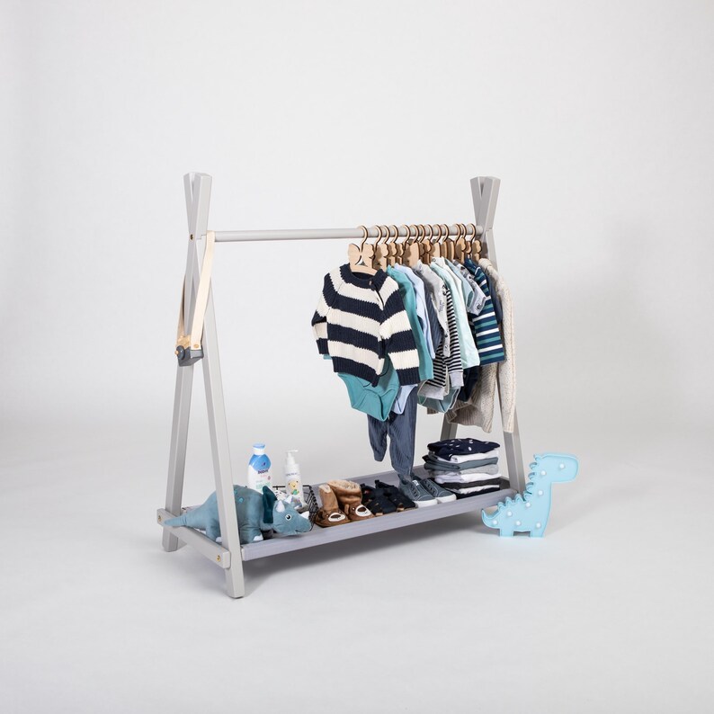 Grey wooden wardrobe stand displaying toddler sweaters and shoes, perfect for godparents gifting durable solid wood furniture.
