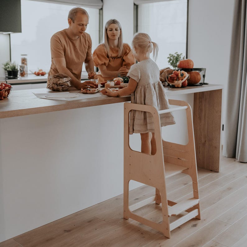Natural wood look montessori standing tower surrounded by family at the island, creating a warm bonding experience during Thanksgiving prep.