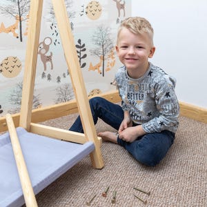 Young boy resting beside timber wardrobe components during setup, demonstrating a simple assembly process for foster parents.