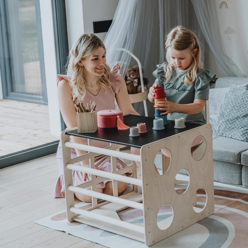 Mother and young daughter engaging in creative play around a multifunctional cube table.