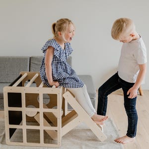 A boy and a girl practicing gross motor skills while climbing an indoor play gym.