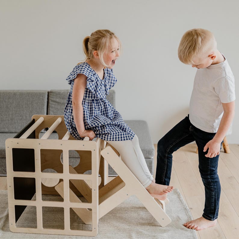 A boy and a girl practicing gross motor skills while climbing an indoor play gym.
