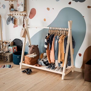 Natural timber coat rack positioned against a blue wave wall, solving daily clothing mess for energetic preschool boys.