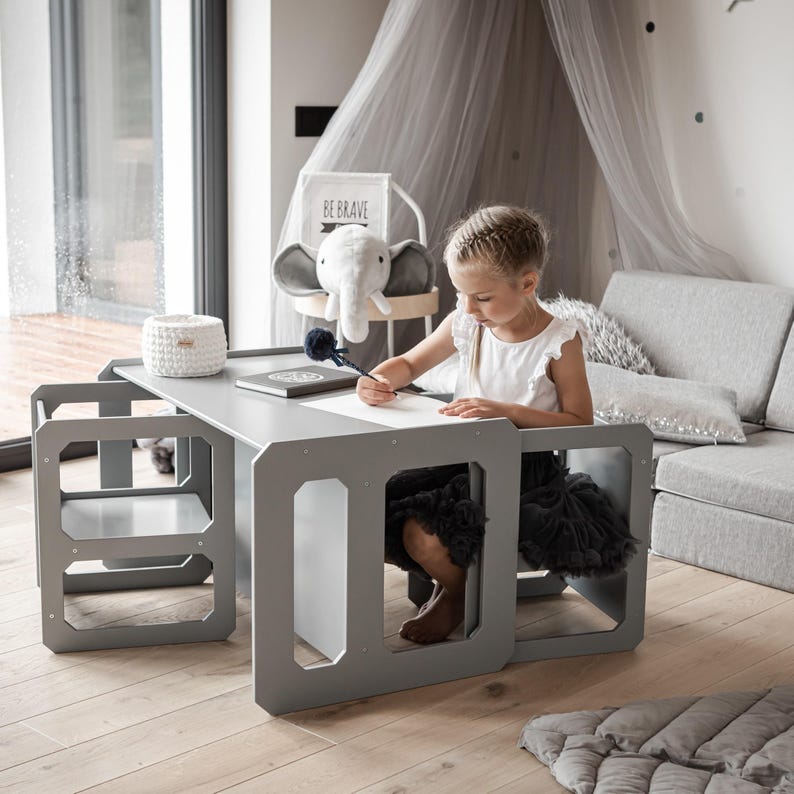 Girl drawing at a grey painted activity desk with matching cube chairs.