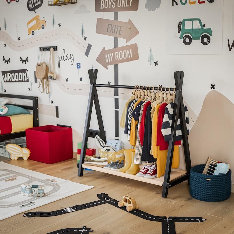 Black timber clothes stand styled with jackets near a toy road rug, presenting a unique Name Day gift idea for active toddlers.