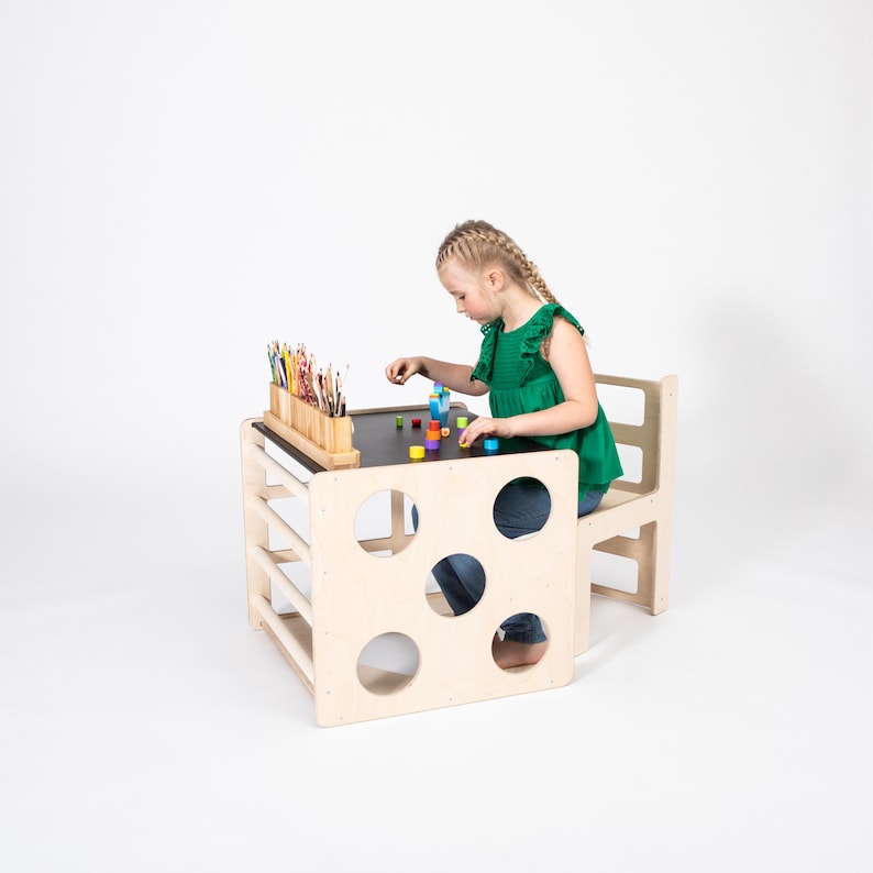Young girl drawing with colorful pencils at a natural birch plywood convertible cube table in studio.