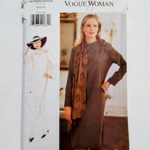 May include: A vintage Vogue Woman sewing pattern. The pattern features a woman in a long-sleeved, dark gray dress with a patterned scarf. The pattern also includes a drawing of a woman in a white dress and hat. The pattern size is 6-8-10.