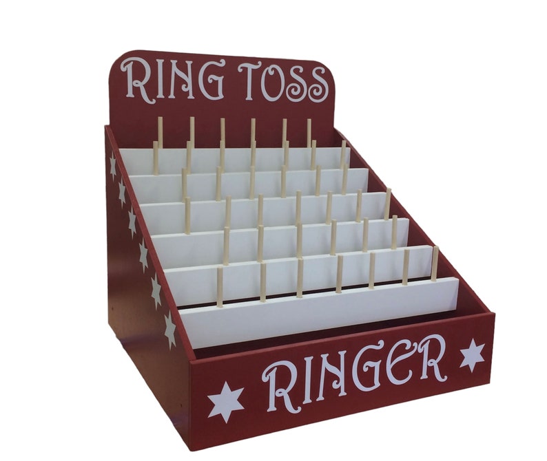 以下が含まれることがあります： 赤い木製のリングトスゲーム。白い星と「Ring Toss」と「Ringer」の文字が前面に書かれています。