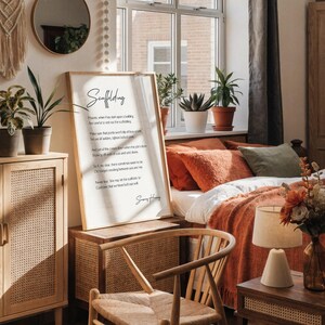 a framed poem titled "Scaffolding" displayed on a white desk, accompanied by a notebook, a cup, and a vase with dried flowers.