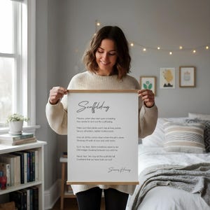a framed poem titled "Scaffolding" displayed on a white desk, accompanied by a notebook, a cup, and a vase with dried flowers.