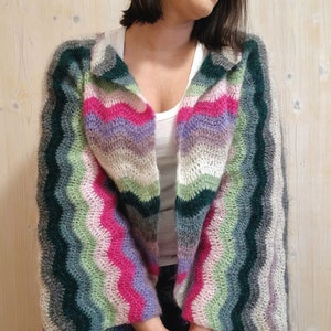 May include: A multi-coloured striped crochet cardigan with a long, open front and bell sleeves. The cardigan is made with a soft, fuzzy yarn and features a wavy stitch pattern.
