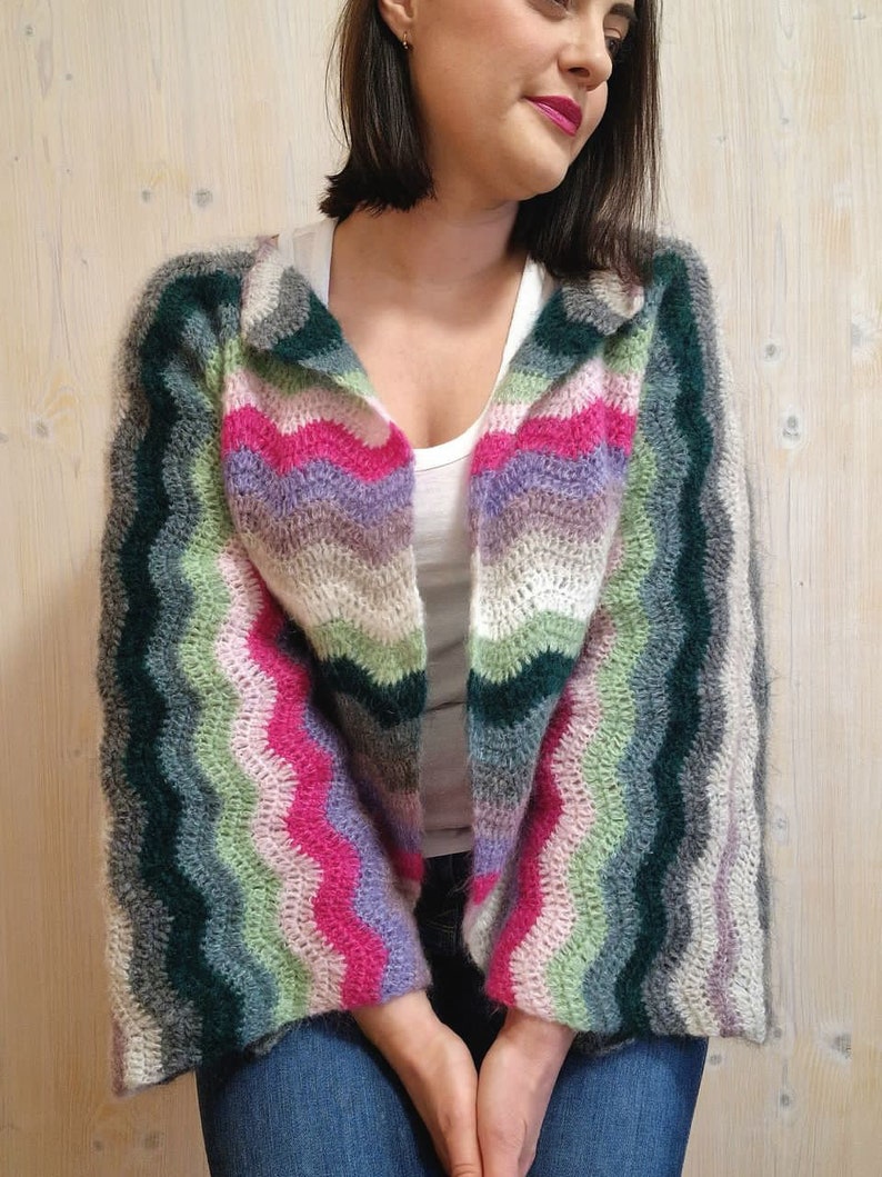 May include: A multi-coloured striped crochet cardigan with a long, open front and bell sleeves. The cardigan is made with a soft, fuzzy yarn and features a wavy stitch pattern.