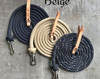 May include: Three coiled ropes with leather ends and metal clasps. The ropes are black, beige, and black with beige speckles. The ropes are labeled "Black", "Beige", and "Black with Beige".