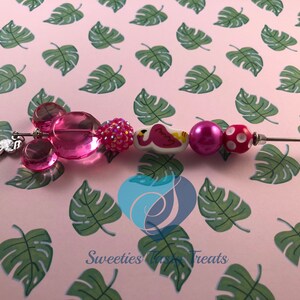 以下が含まれることがあります： ピンクとシルバーのチャームブレスレット。フラミンゴ、ミッキーマウスの耳、キラキラ光るビーズが付いています。Sweeties Treats.