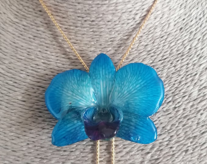blue orchid embedded in resin and finished with gold on bronze adjustable slider