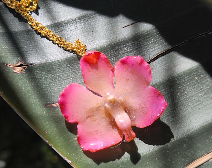 Pink Vanda orchid resin necklace embedded in resin and finished with a gold-plated bronze chain.