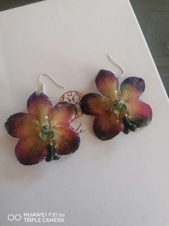 Earrings made with natural orchids incorporated in resin and silver hooks.