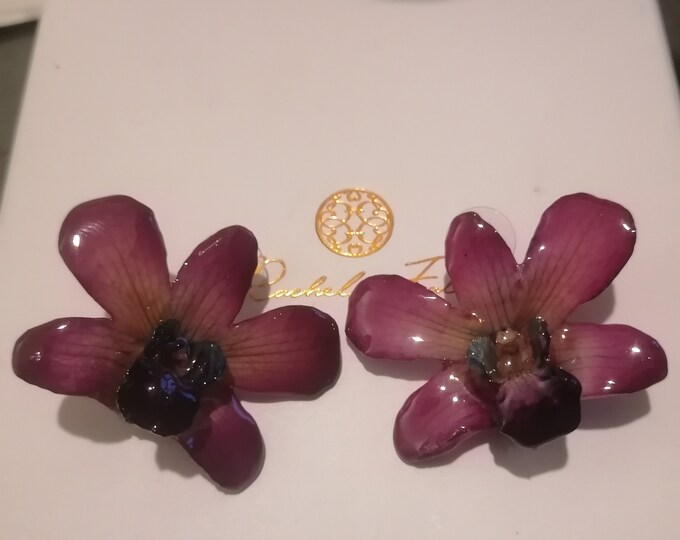 Purple orchid ear studs with blue reflections embedded in resin with silver hooks