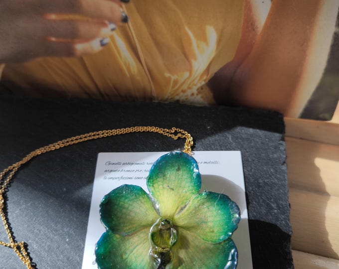 Green/blue Vanda orchid with yellow reflections embedded in resin and finished with a gold chain in galvanic on bronze.