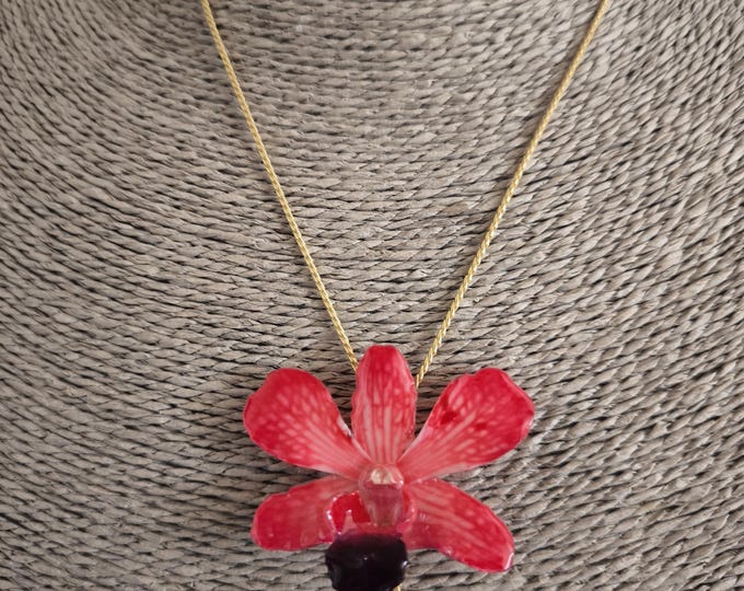 spectacular small red/lobster orchid embedded in resin and finished with gold on bronze adjustable slider.