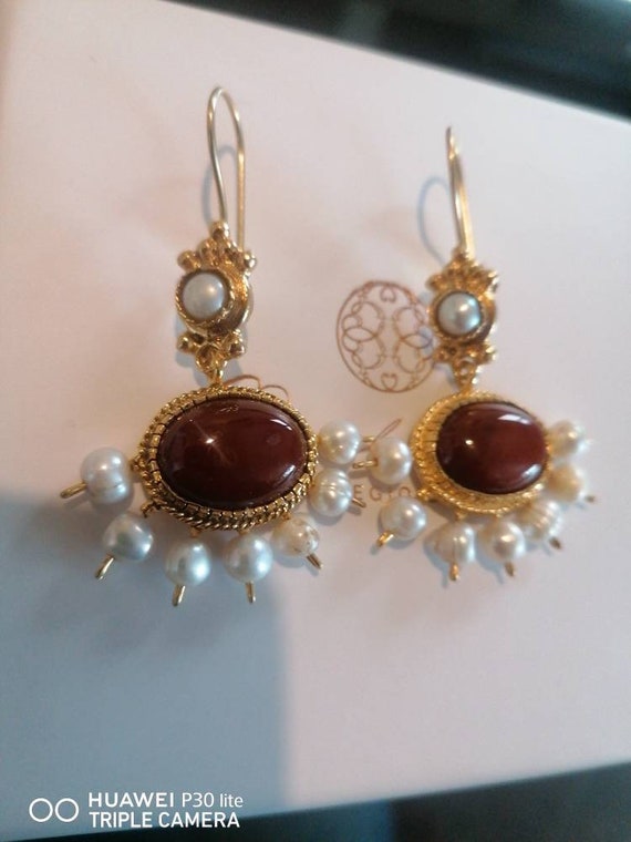 Spectacular pair of earrings in matte gold on bronze and finished with natural pearls and carnelian of the highest quality.