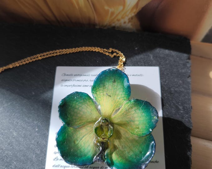 Green/blue Vanda orchid with yellow reflections embedded in resin and finished with a gold chain in galvanic on bronze.