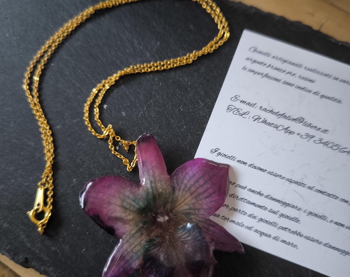 Purple nobilis orchid necklace with blue reflections embedded in resin complete with gold chain on nickel-free bronze.