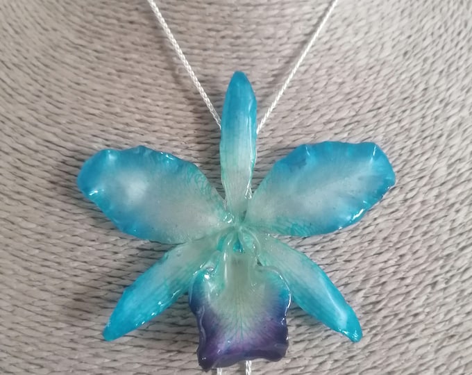 blue/white orchid embedded in resin and finished with adjustable silver-on-bronze slider.