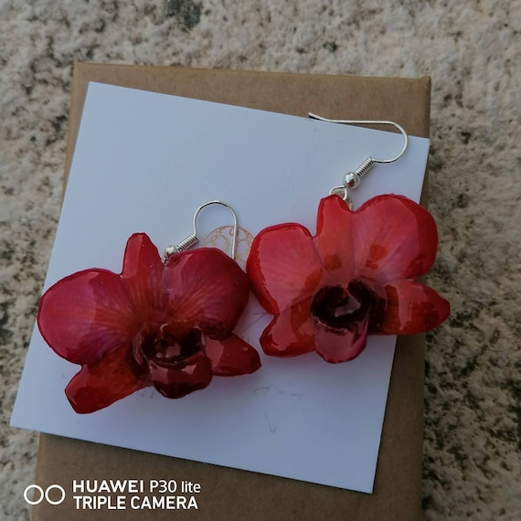 Pair of earrings made with natural orchids embedded in red resin with pink reflections, silver hooks