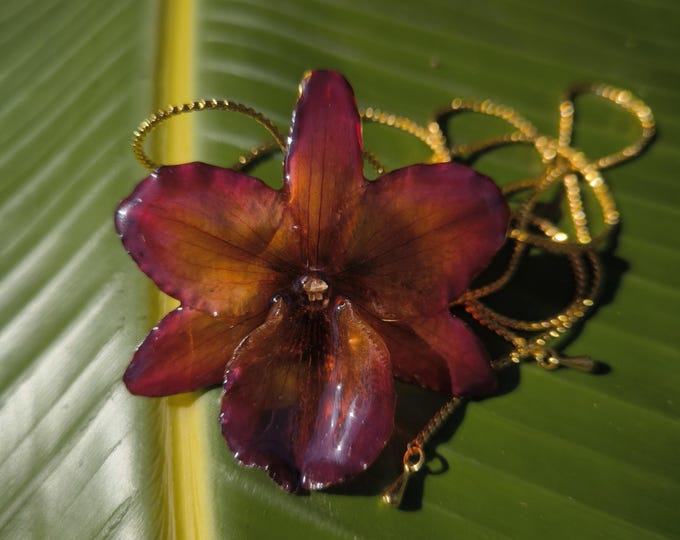 Autumnal brown orchid embedded in resin and finished with adjustable gold-on-bronze sliders