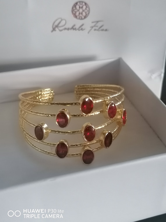 Adjustable bracelet with gold threads on bronze and finished with faceted natural red garnets