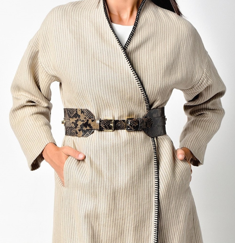 May include: A beige striped wrap coat with a zipper closure and a brown and black snake print belt.