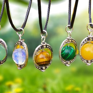 May include: Seven necklaces with silver pendants featuring a rotating sphere of different colored gemstones. The gemstones include black lava rock, green jade, white opal, tiger's eye, green malachite, yellow jasper, and blue lapis lazuli.