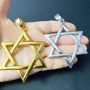 May include: Two Star of David pendants, one gold and one silver. Both pendants are made of metal and have a detailed design.