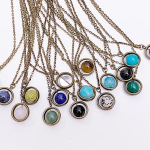 May include: A collection of 15 necklaces with a variety of gemstone beads, each encased in a spinning brass cage. The beads include lapis lazuli, turquoise, agate, tiger's eye, and more.