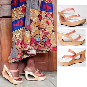 Pode incluir: Três pares de sandálias de plataforma de madeira com tiras laranja. As sandálias têm um design único com uma plataforma grande e aberta.