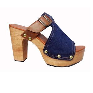 Könnte beinhalten: Blaue Jeans- und braune Leder-Plateau-Sandalen mit Schnalle und goldenen Nieten. Die Sandalen haben eine Holzplattform und einen Holzabsatz.