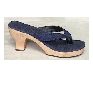 Könnte beinhalten: Ein Paar blaue Jeans-Plattformsandalen mit einem Holzabsatz und einem schwarzen Riemen.