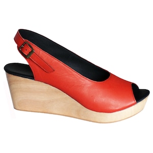 May include: Red leather wedge sandal with a wooden platform and a slingback strap. The sandal has an open toe design.