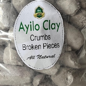 May include: A close-up of a bag of Ayilo Clay Crumbs and Broken Pieces. The bag is clear plastic and the clay is a light gray color. The label on the bag says "Ayilo Clay Crumbs Broken Pieces All Natural".