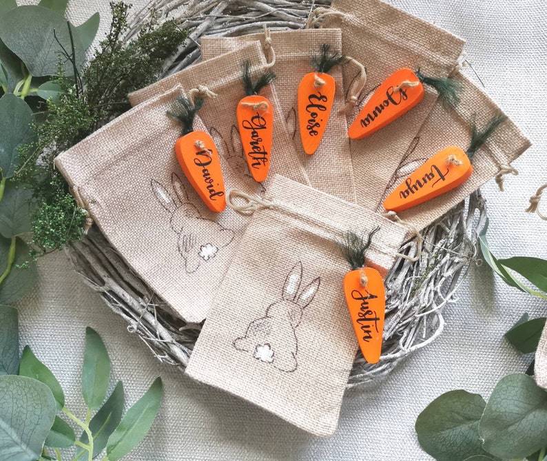 May include: Set of 6 burlap gift bags with carrot-shaped tags. The tags are decorated with the names "Garrett", "Eloise", "Justin", "David", "Tonia", and "Jowin".