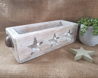 Può includere: Scatola di legno bianca con finitura rustica e tre tagli a forma di stella. La scatola ha una maniglia in metallo sul lato.