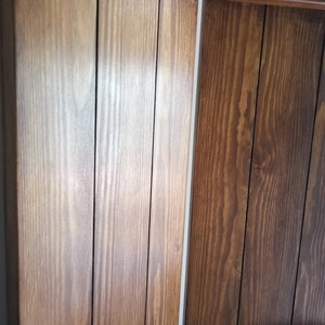 May include: Close-up of a wooden room divider with a natural brown stain. The divider is made of vertical wooden planks with a smooth finish.