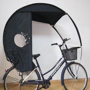 May include: A navy blue bicycle with a black canopy and a basket. The canopy has a clear window and provides shade. The bicycle has the word "FOREVER" printed on the frame.